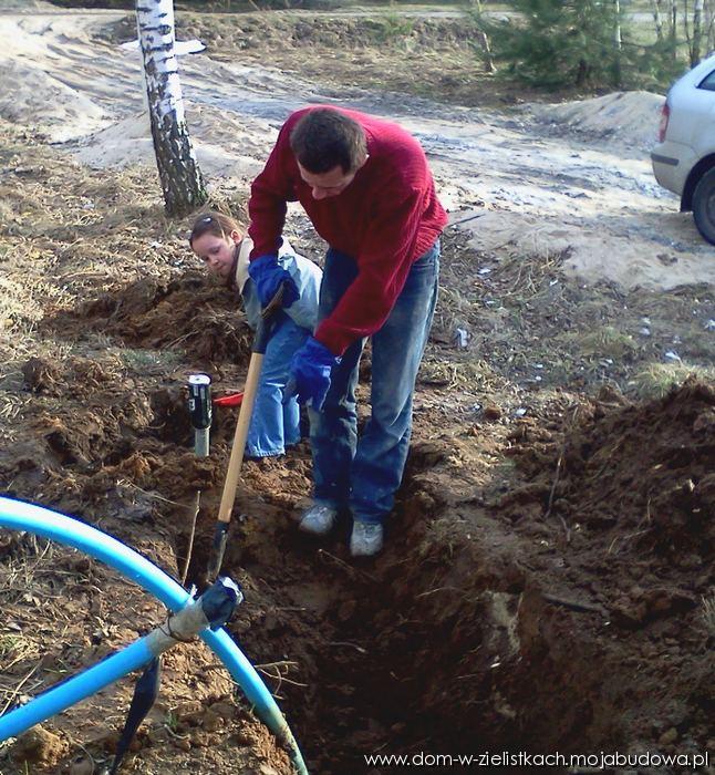 Córka pomaga tacie wykopywac rurę z ziemii